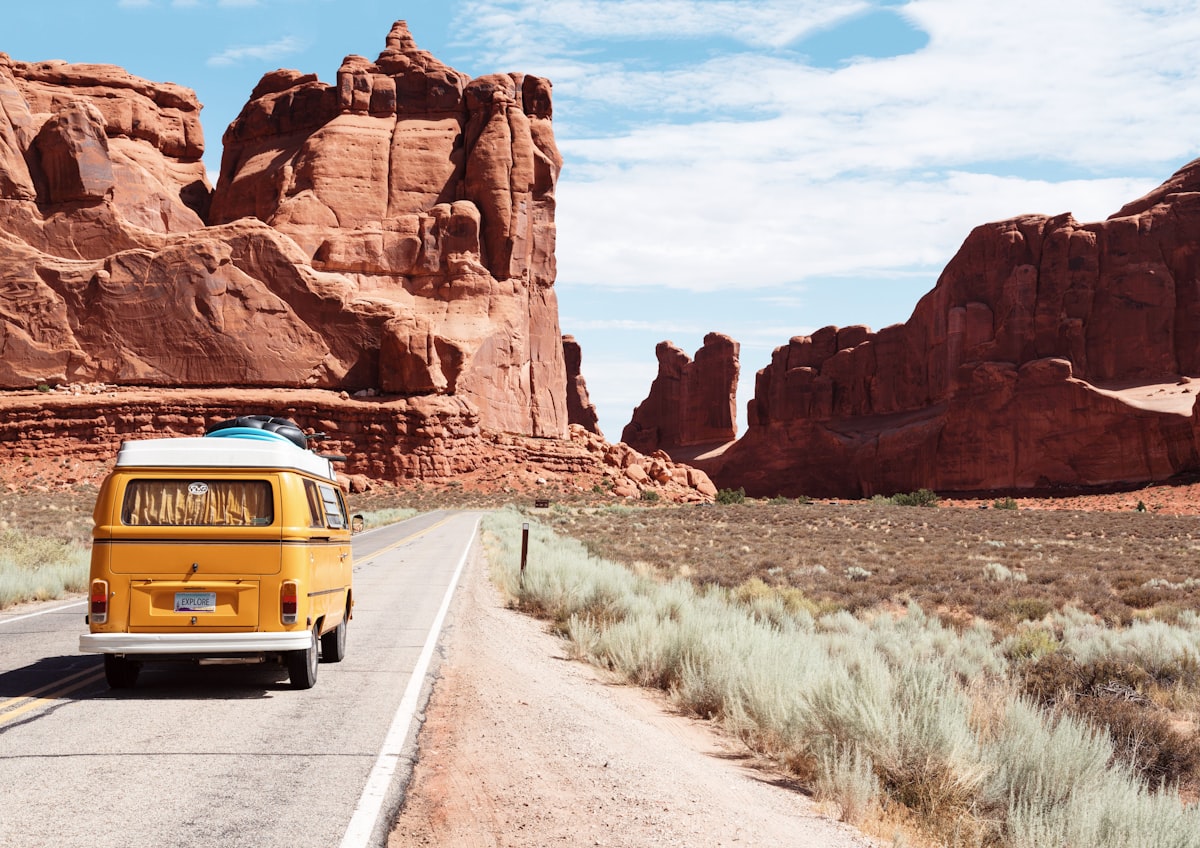 A yellow VW van driving down an open desert highway — the freedom of the open road