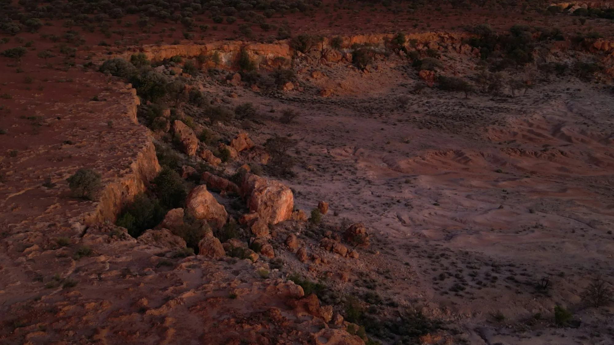 Wide view looking down into a canyon at dusk, layers of rock receding into shadow