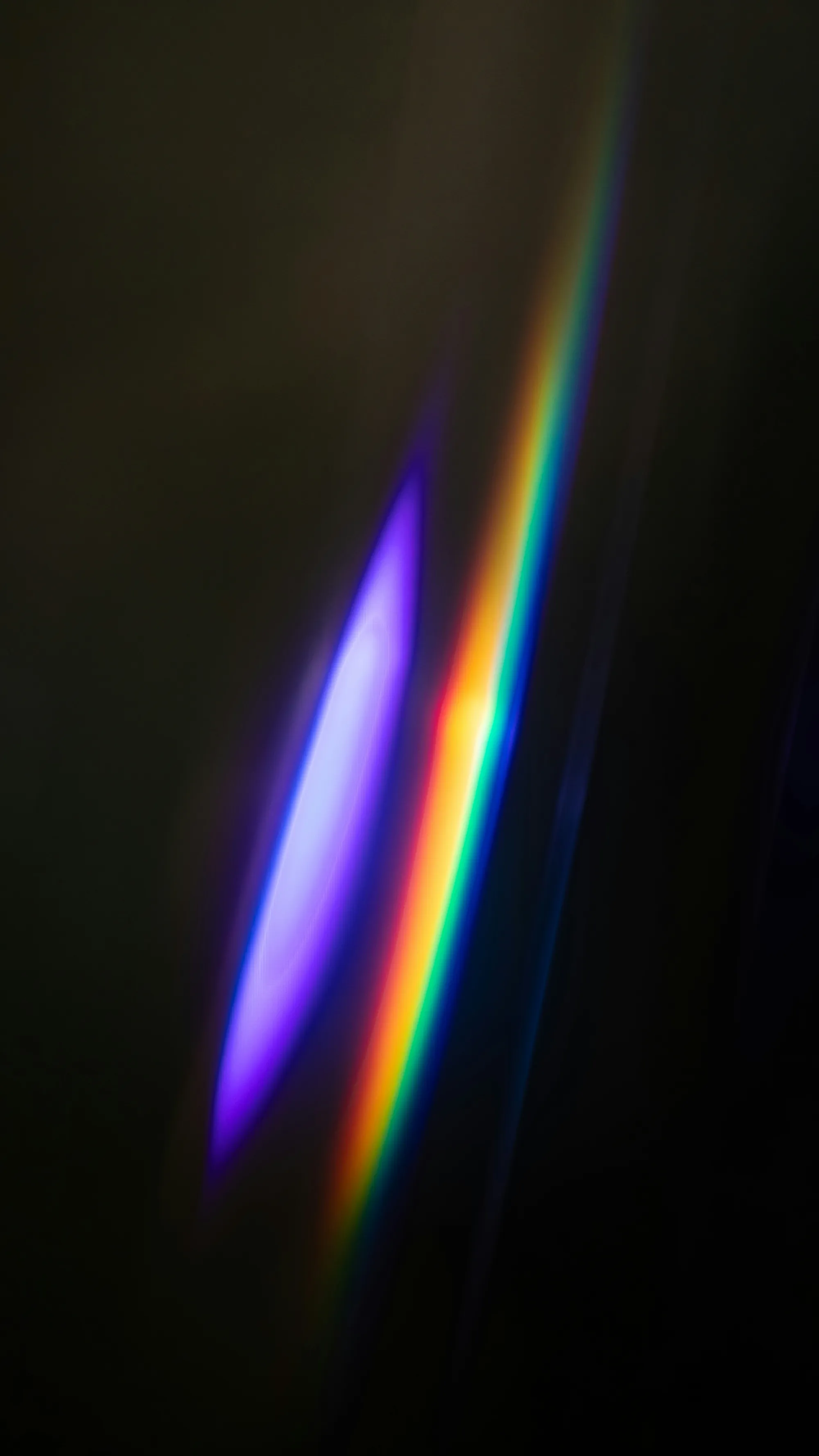 Light refracting through a prism against darkness